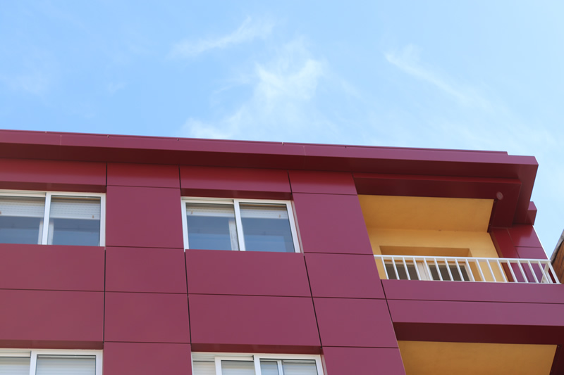 Imagen de detalle de la envolvente de edificio en A Estrada con colores potentes para este edificio de viviendas